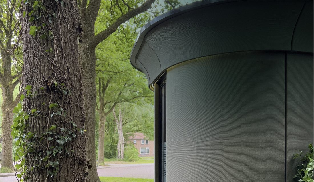 Detail van een donkere Pulse-gevel naast een boomstam